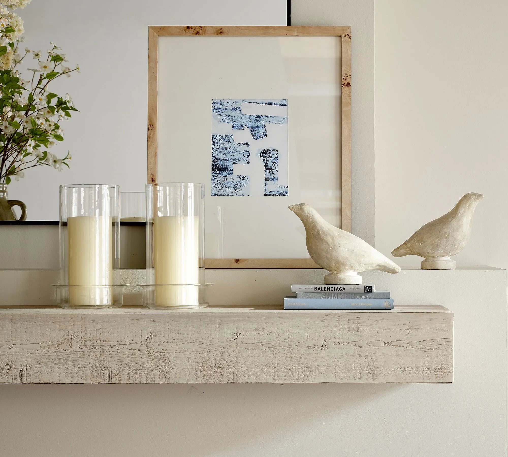 Elegant wall shelf decorated with framed art, candles, and sculptures