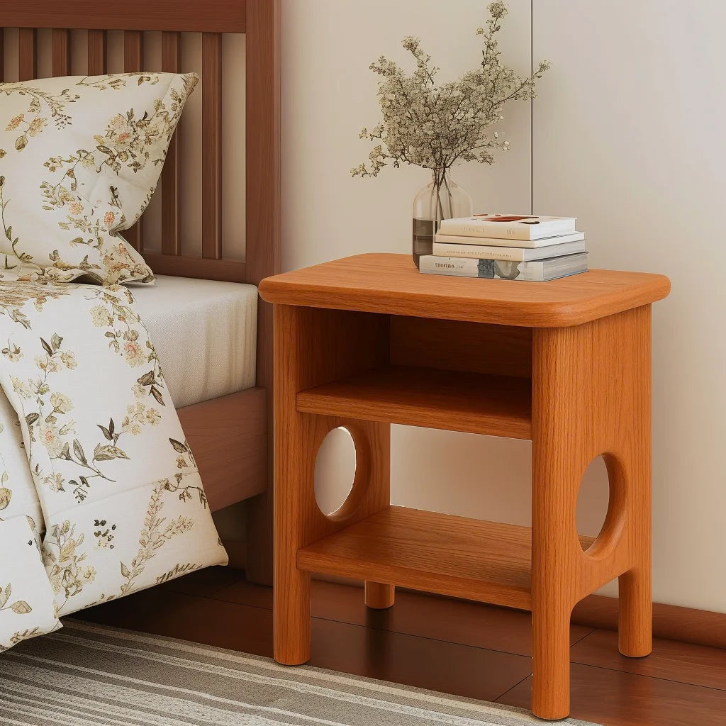 Rounded nightstand with open shelving and sculptural cutout legs in a cozy bedroom corner